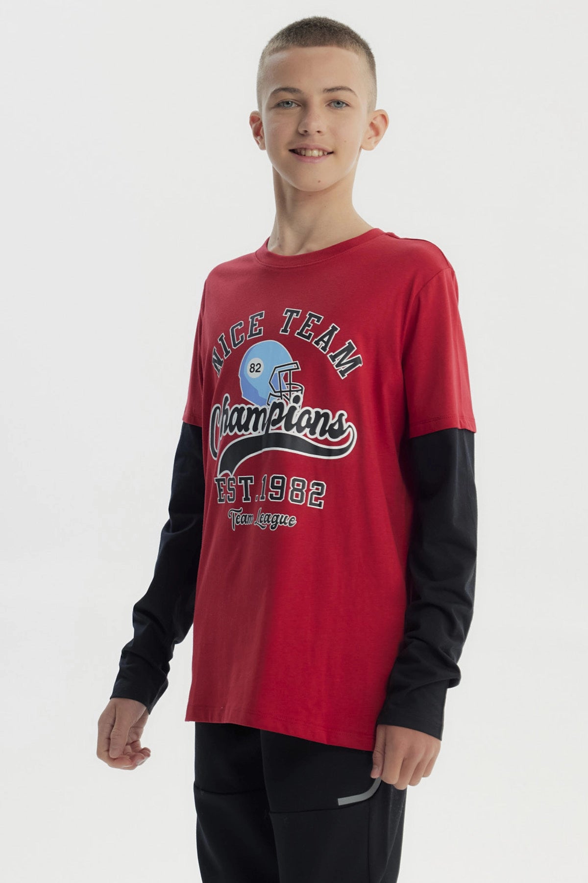 Polera niño roja oscura con diseño de casco de fútbol y texto Nice Team Champions en el centro estilo deportivo