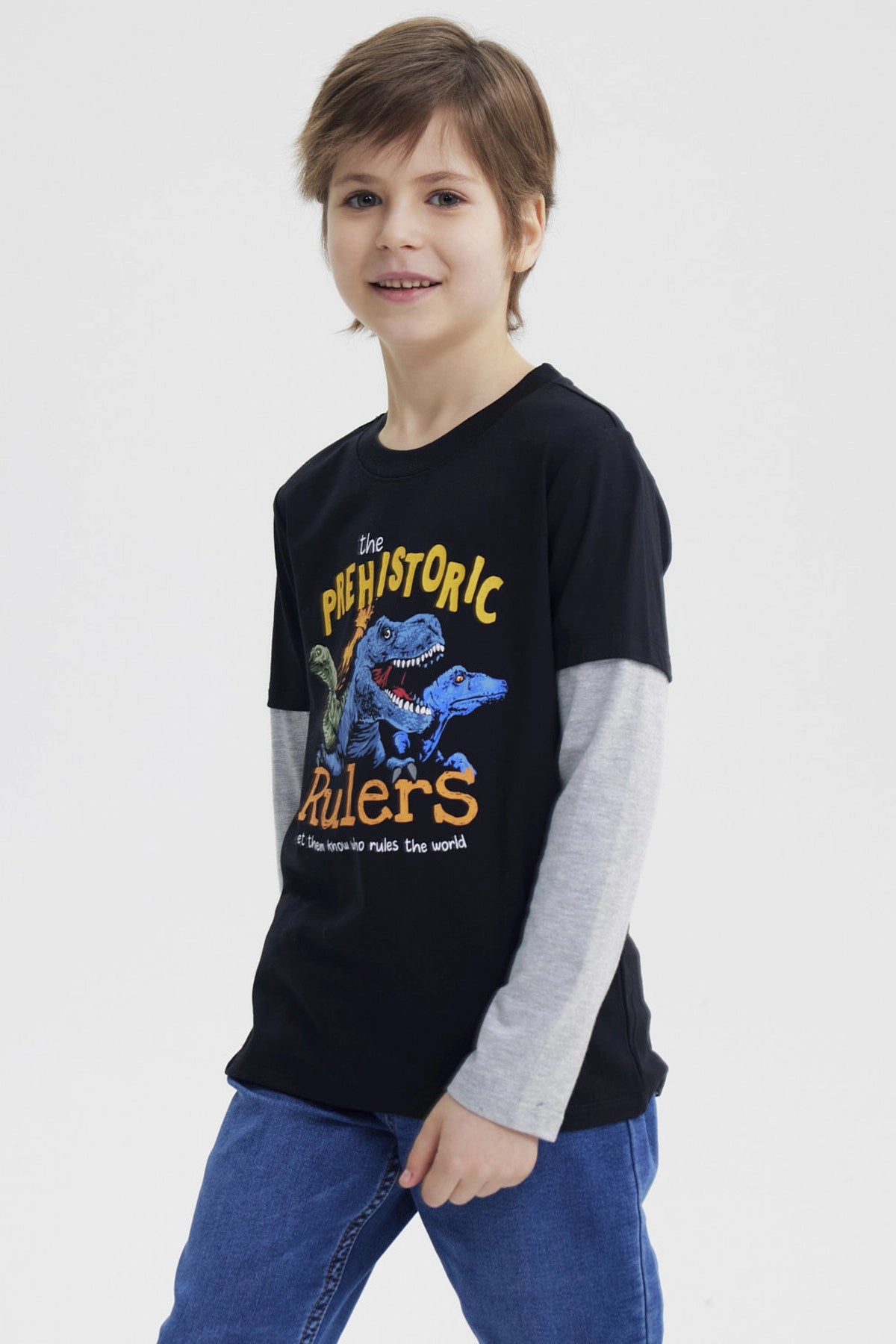 Polera niño negra con estampado de dinosaurios azules en el pecho estilo gráfico grande y texto The Prehistoric Rulers