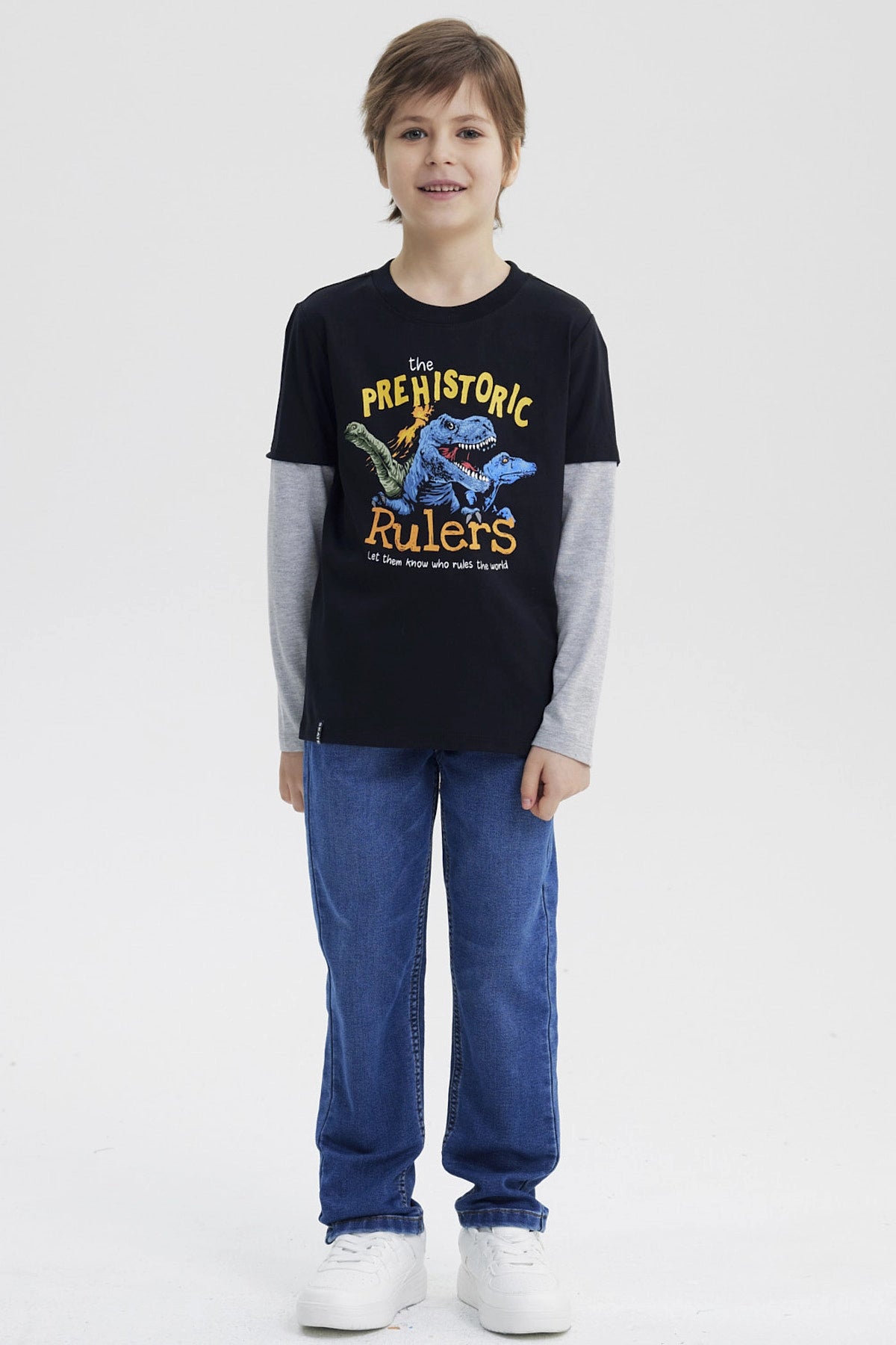 Polera niño negra con estampado de dinosaurios azules en el pecho estilo gráfico grande y texto The Prehistoric Rulers