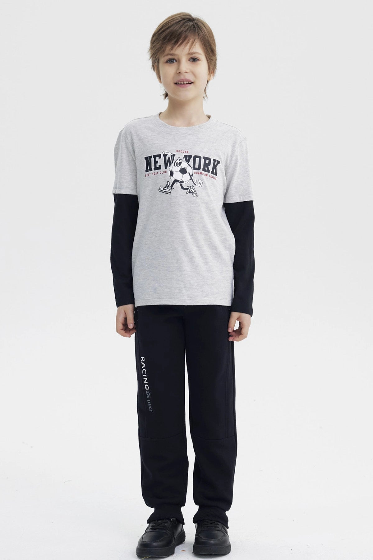 Polera niño gris melange claro con estampa central New York y personaje con balón en estilo gráfico animado