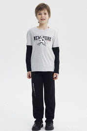 Polera niño gris melange claro con estampa central New York y personaje con balón en estilo gráfico animado