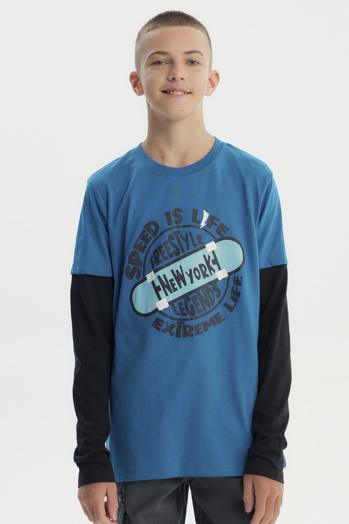 Polera niño color petróleo con estampa central de skate y texto Speed is life Freestyle New York Legends Extreme Life estilo urbano
