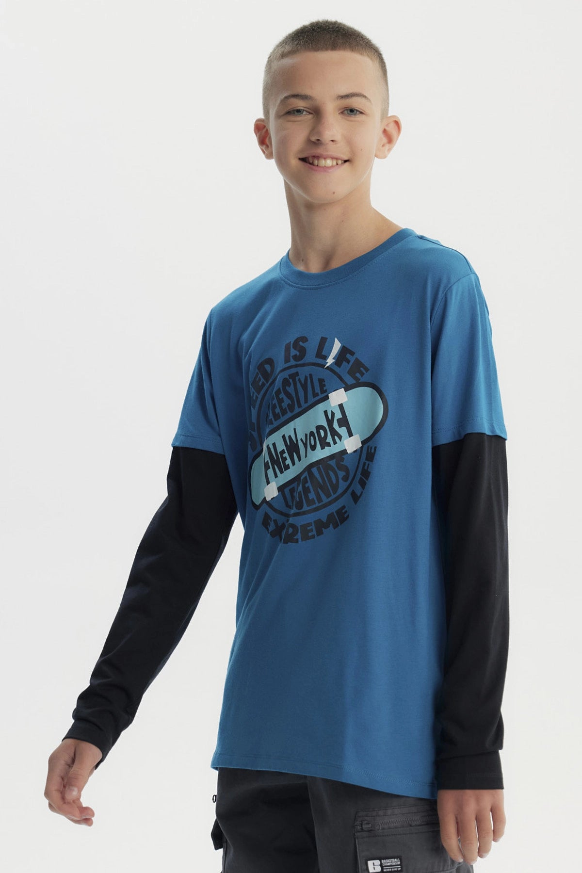 Polera niño color petróleo con estampa central de skate y texto Speed is life Freestyle New York Legends Extreme Life estilo urbano