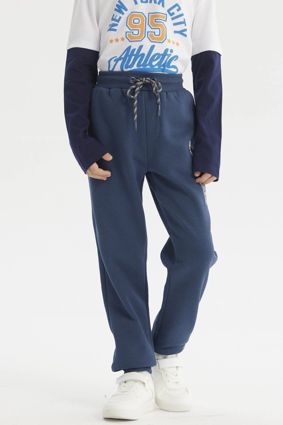 Pantalón buzo niño jogger azul petróleo con cintura elástica y cordón ajustable sin estampa visible diseño liso
