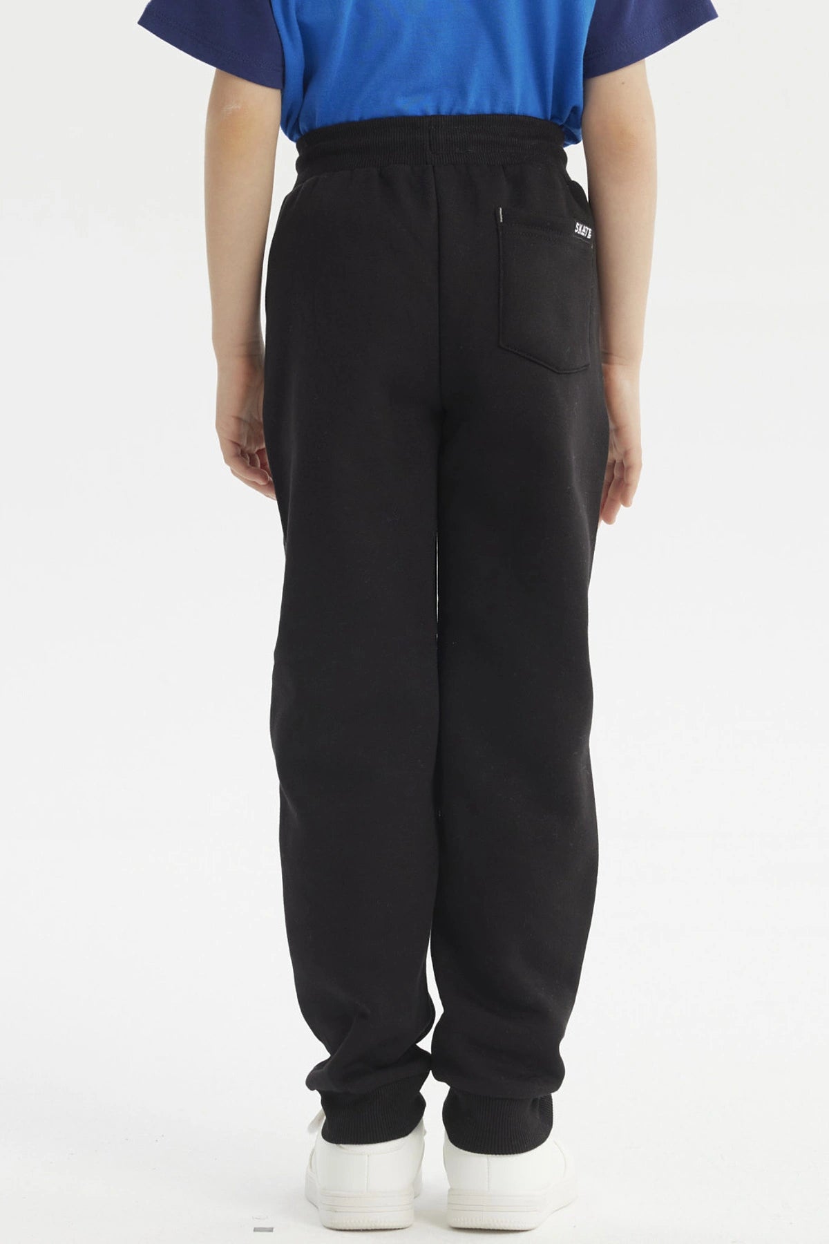 Pantalón buzo negro para niño con diseño de logo en la pierna izquierda estilo casual y cordones ajustables