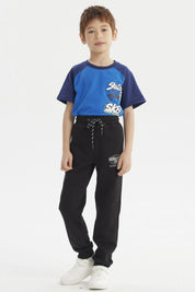 Pantalón buzo negro para niño con diseño de logo en la pierna izquierda estilo casual y cordones ajustables