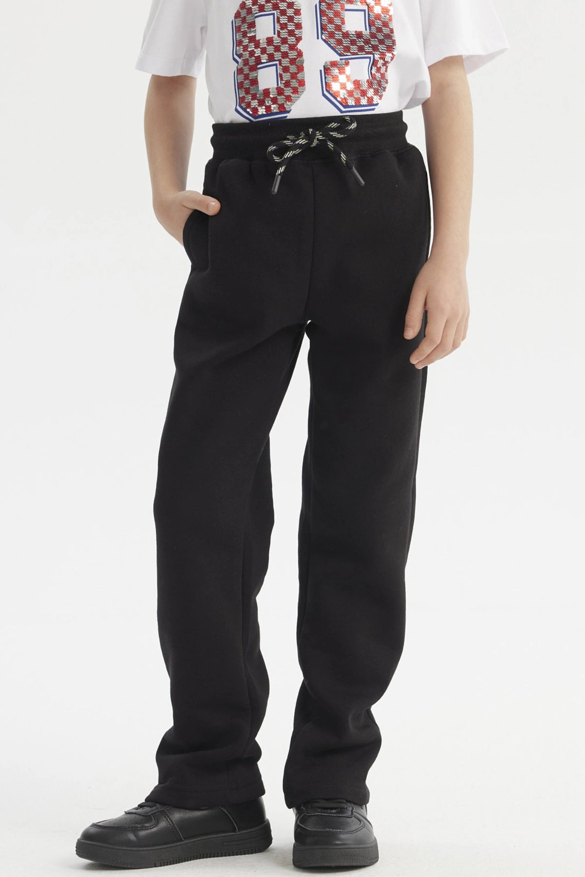 Pantalón buzo niño negro con calce recto y cordón en la cintura prenda lisa ideal para días de juego