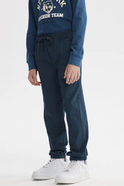 Pantalón niño básico color petróleo con pretina elástica y cordón ajustable diseño liso