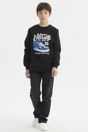 Polerón negro de niño con diseño gráfico grande de zapatilla azul en el frente y texto Super Varsity N.Y. 55