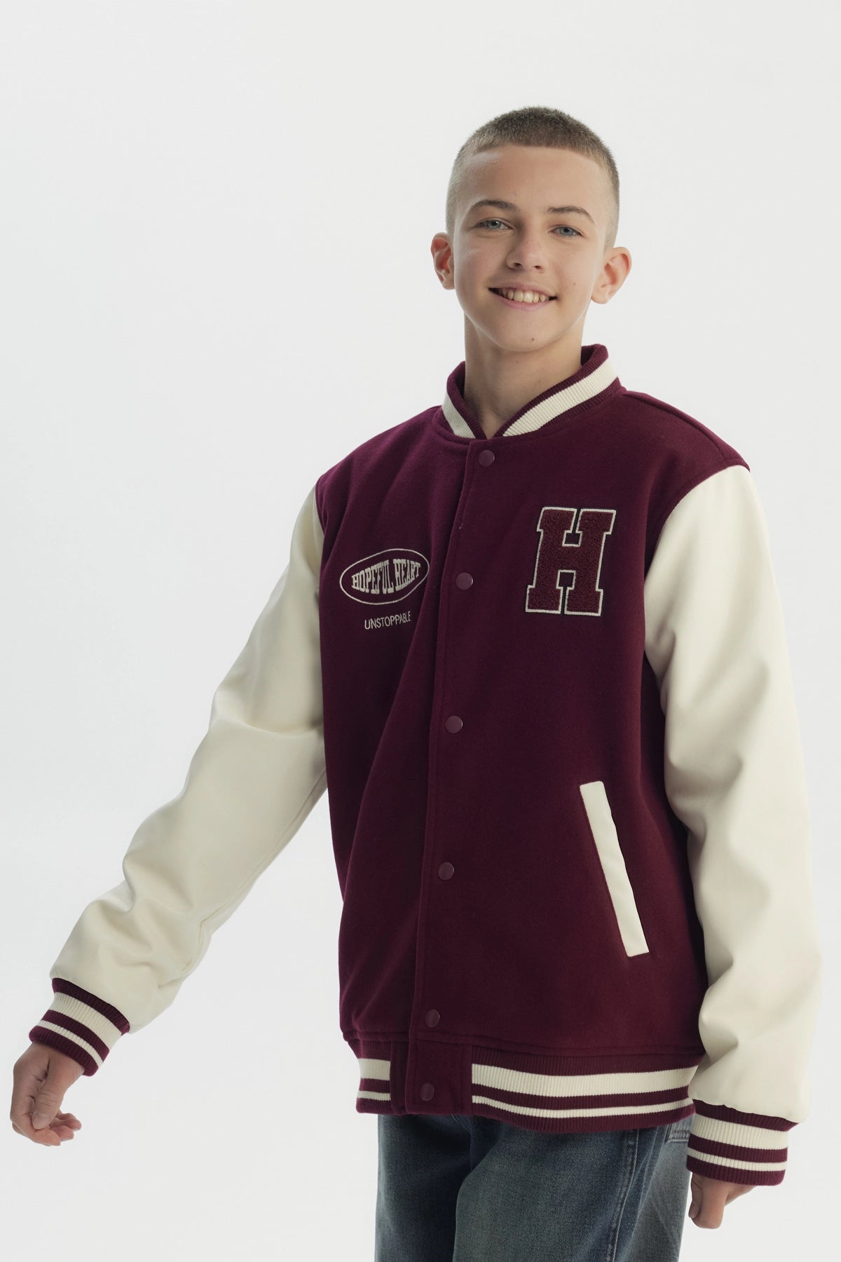 Chaqueta niño burdeo con cuello en V y mangas crema estilo varsity con letra H grande bordada en el pecho