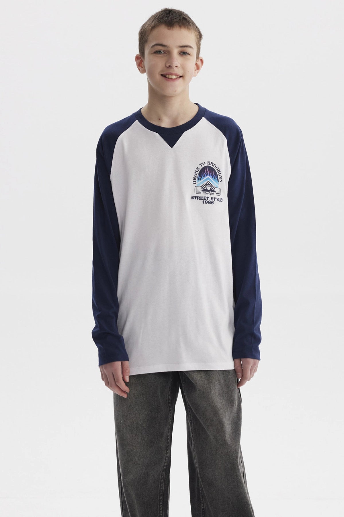 Polera blanca para niño con mangas largas azul marino diseño "Bronx to Brooklyn Street Style 1986" en el pecho