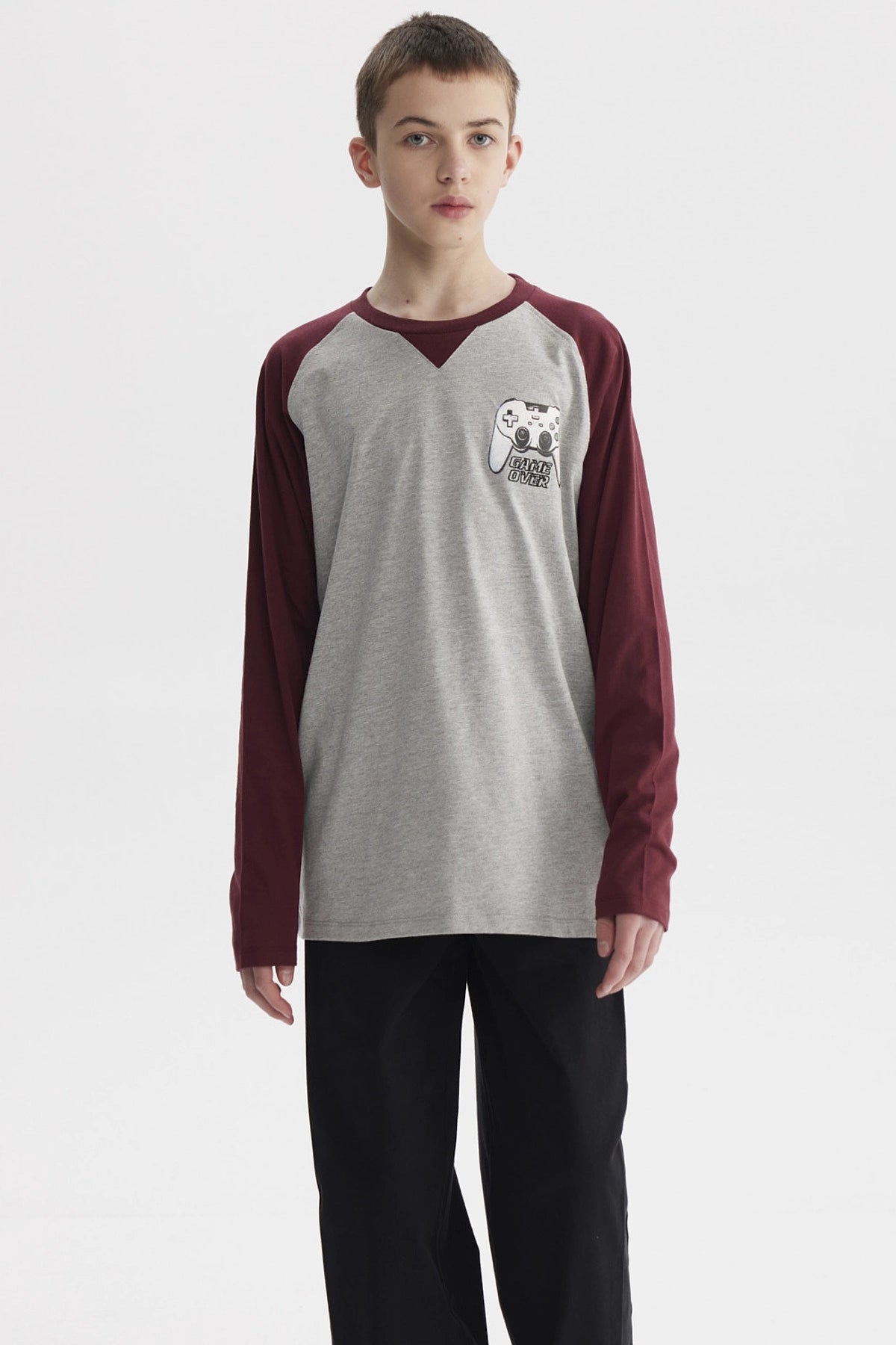 Polera de niño crudo con mangas largas burdeos y estampa pequeña de control de videojuegos en el pecho con texto Game Over