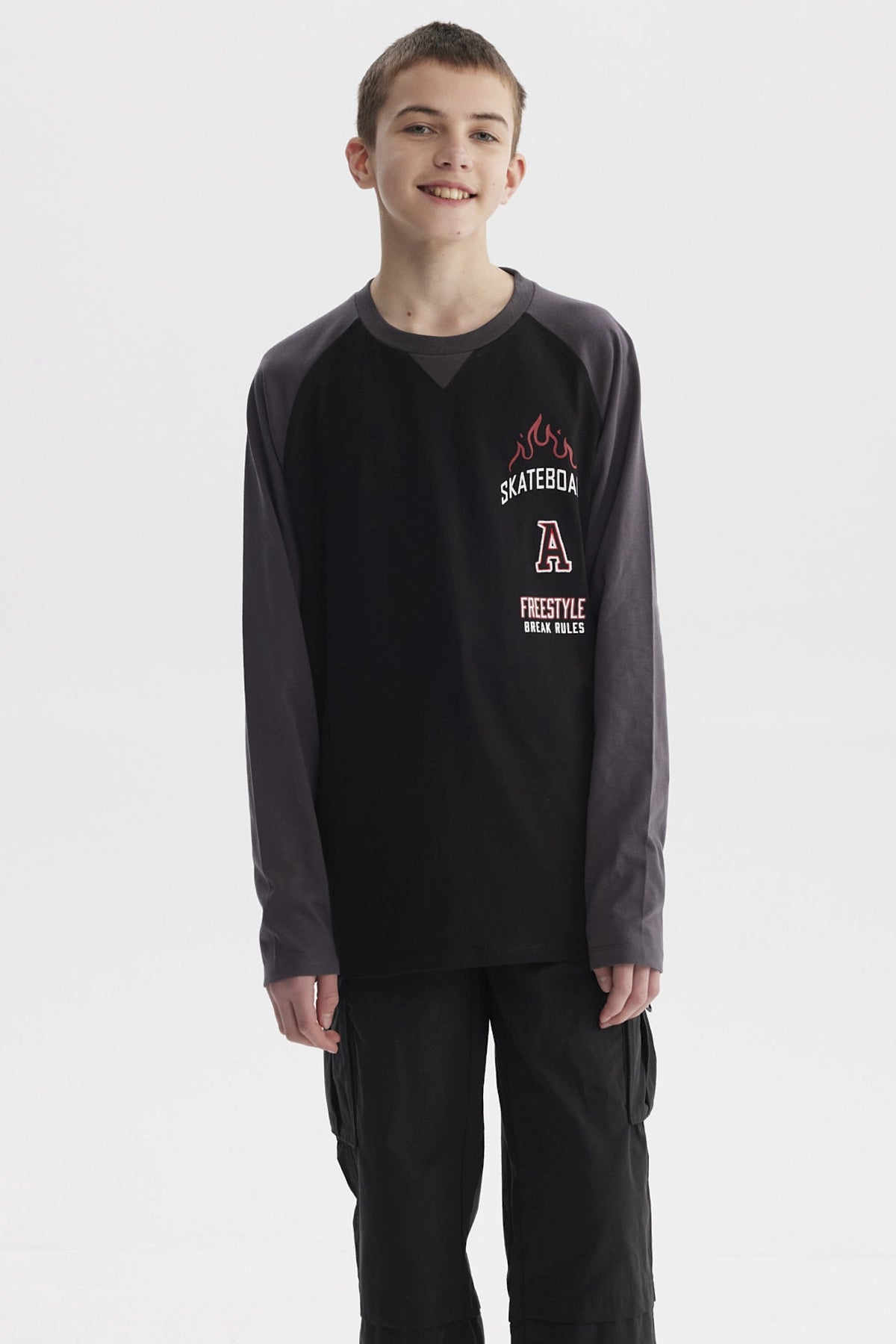 Polera negra para niño con mangas largas gris oscuro y estampado de skate con llamas y texto en el pecho