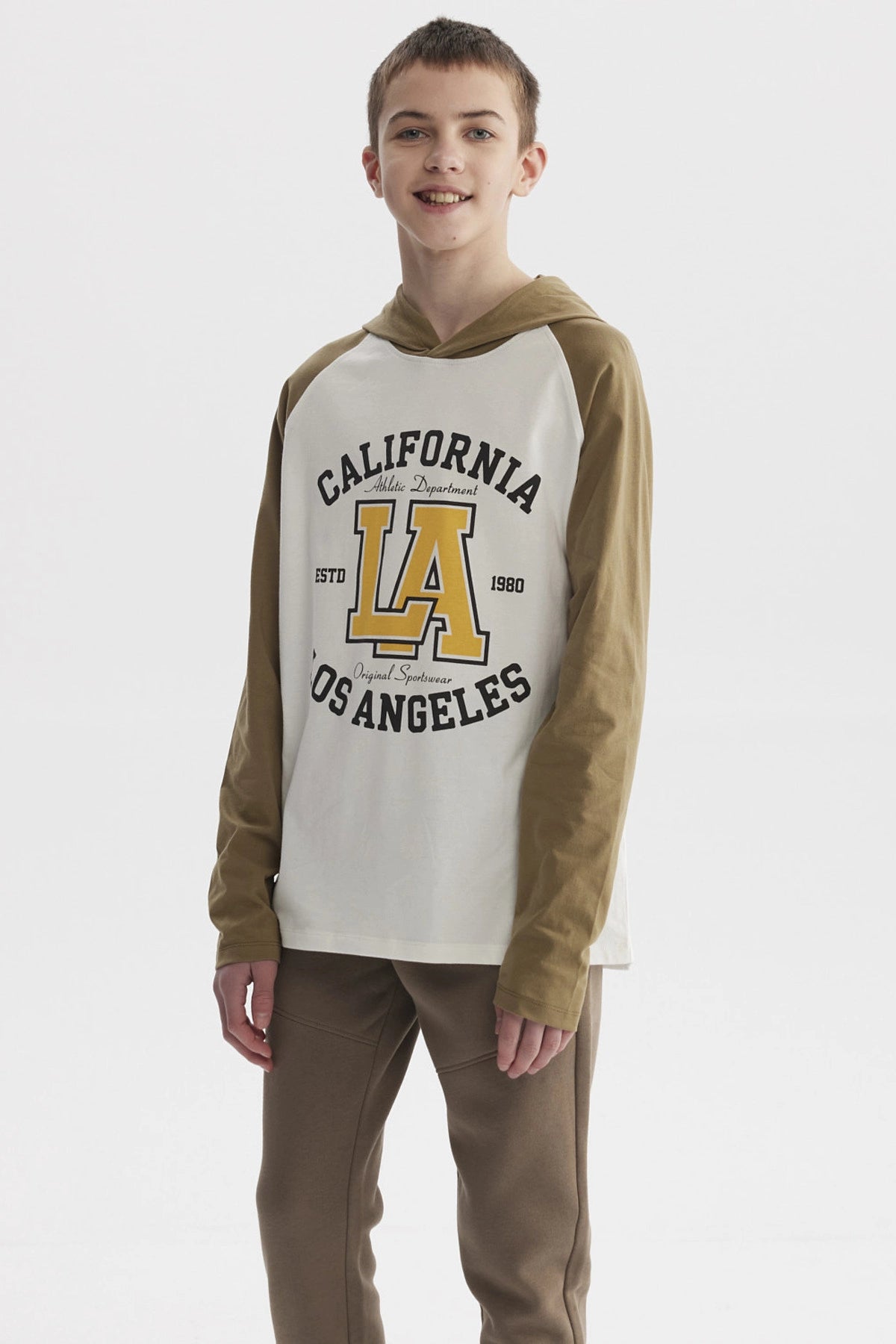 Polera de niño crudo con mangas largas color oliva y estampado central grande de letras y números estilo universitario