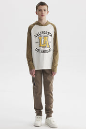 Polera de niño crudo con mangas largas color oliva y estampado central grande de letras y números estilo universitario