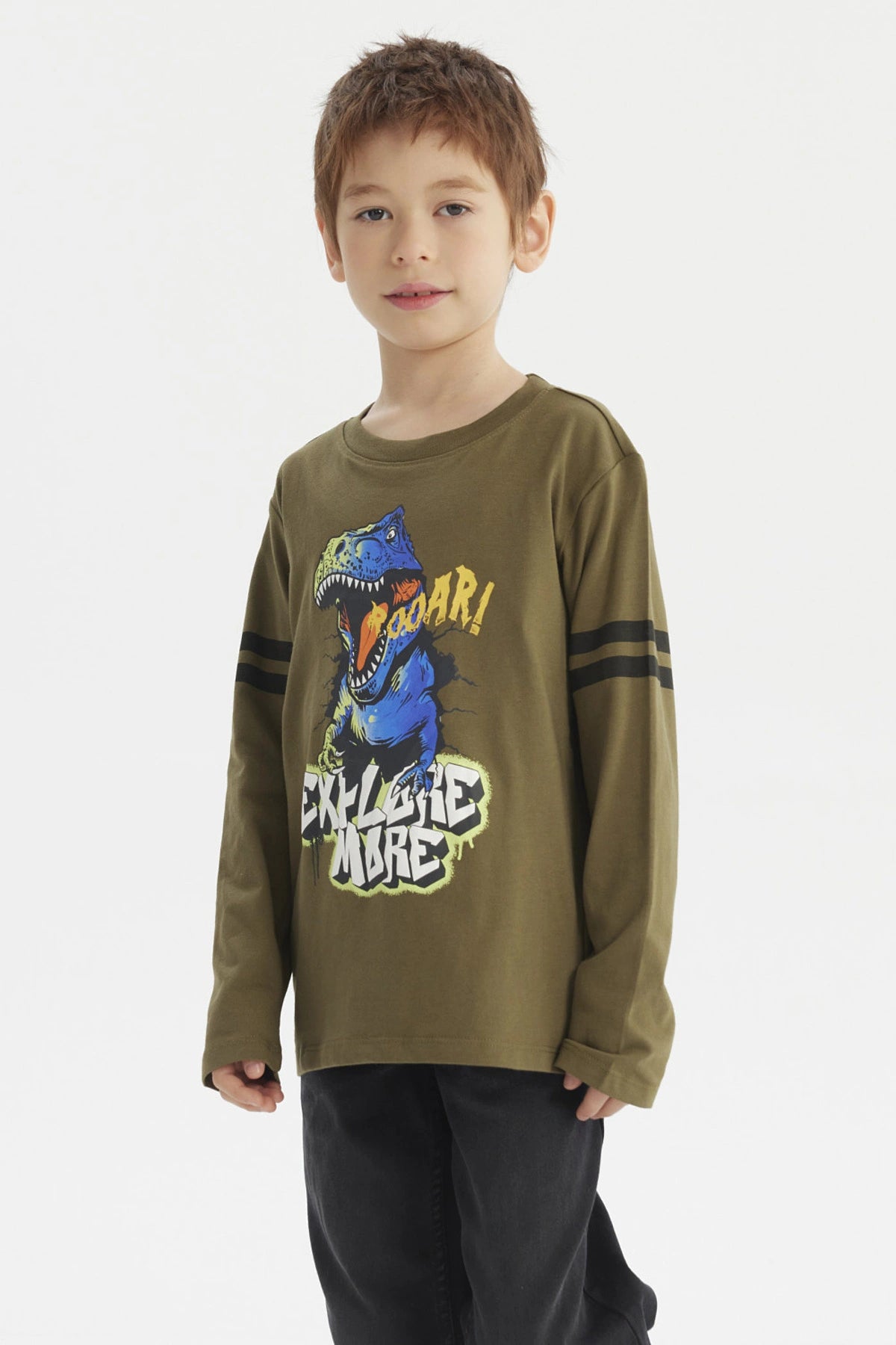 Polera de niño verde militar con dinosaurio azul y texto Roaar Explore More al frente estilo gráfico divertido