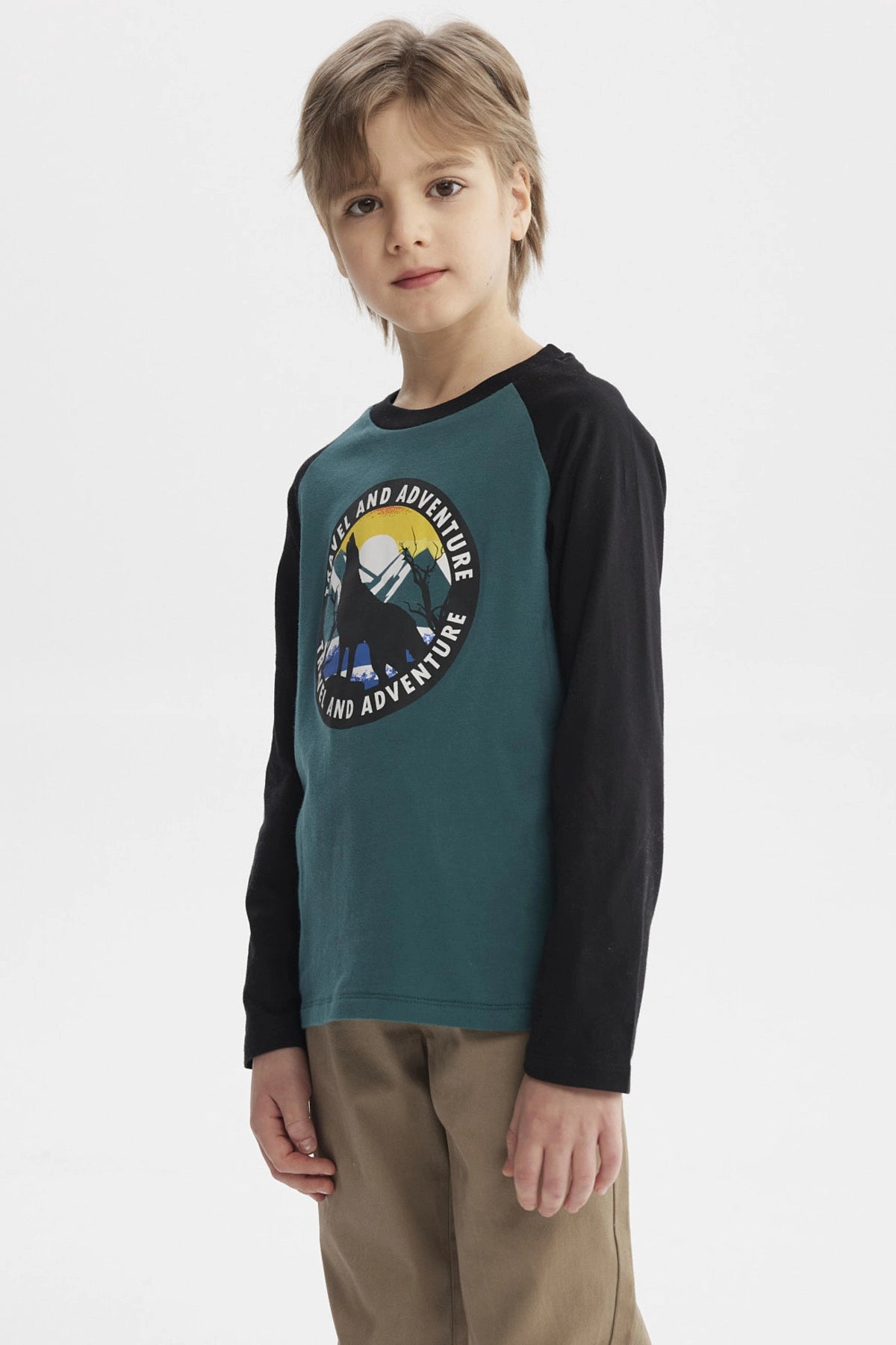 Polera verde oscuro con mangas negras y estampado central de lobo aullando frente a luna llena con texto Travel and Adventure
