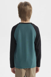 Polera verde oscuro con mangas negras y estampado central de lobo aullando frente a luna llena con texto Travel and Adventure