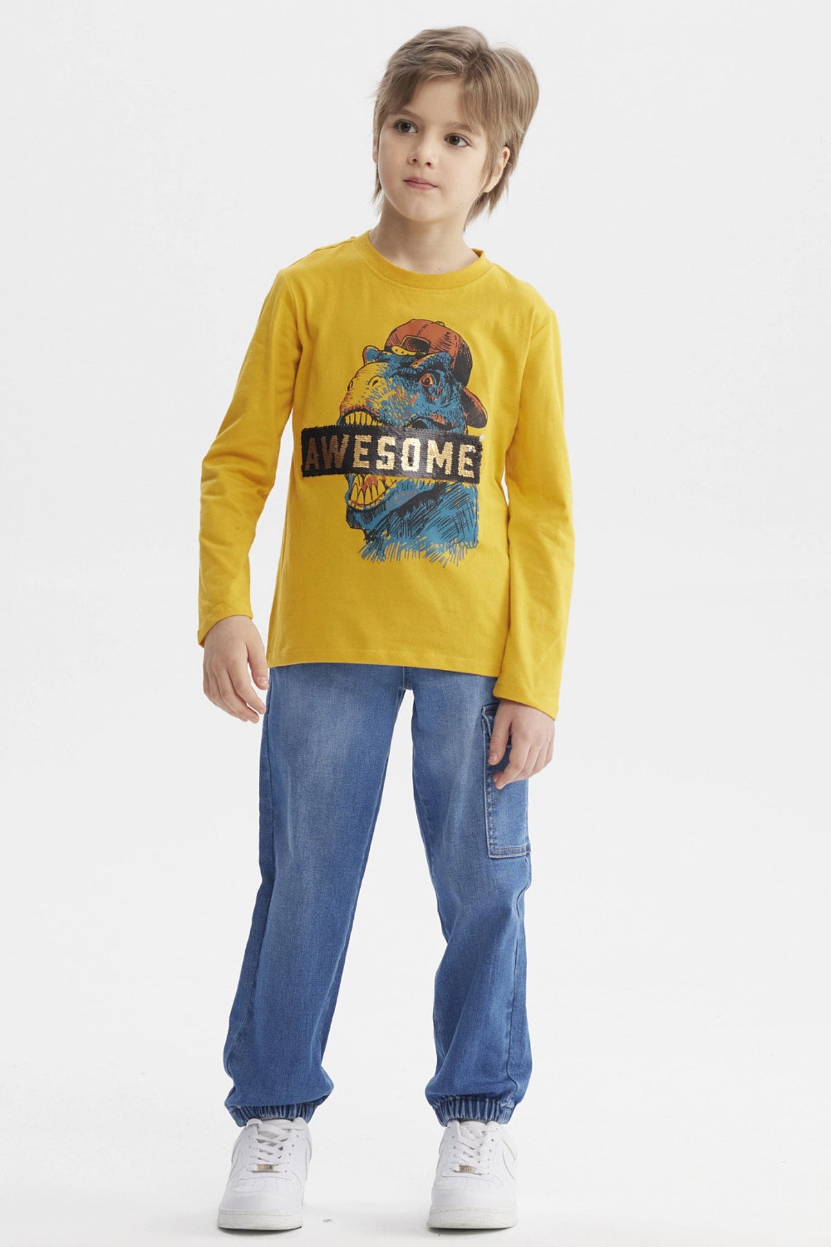 Polera mostaza para niño con estampa de dinosaurio azul y texto AWESOME en el pecho estilo gráfico divertido