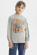 Polera niño gris melange con estampado de dinosaurio geométrico grande al frente letras TYRANOSAURUS en naranja
