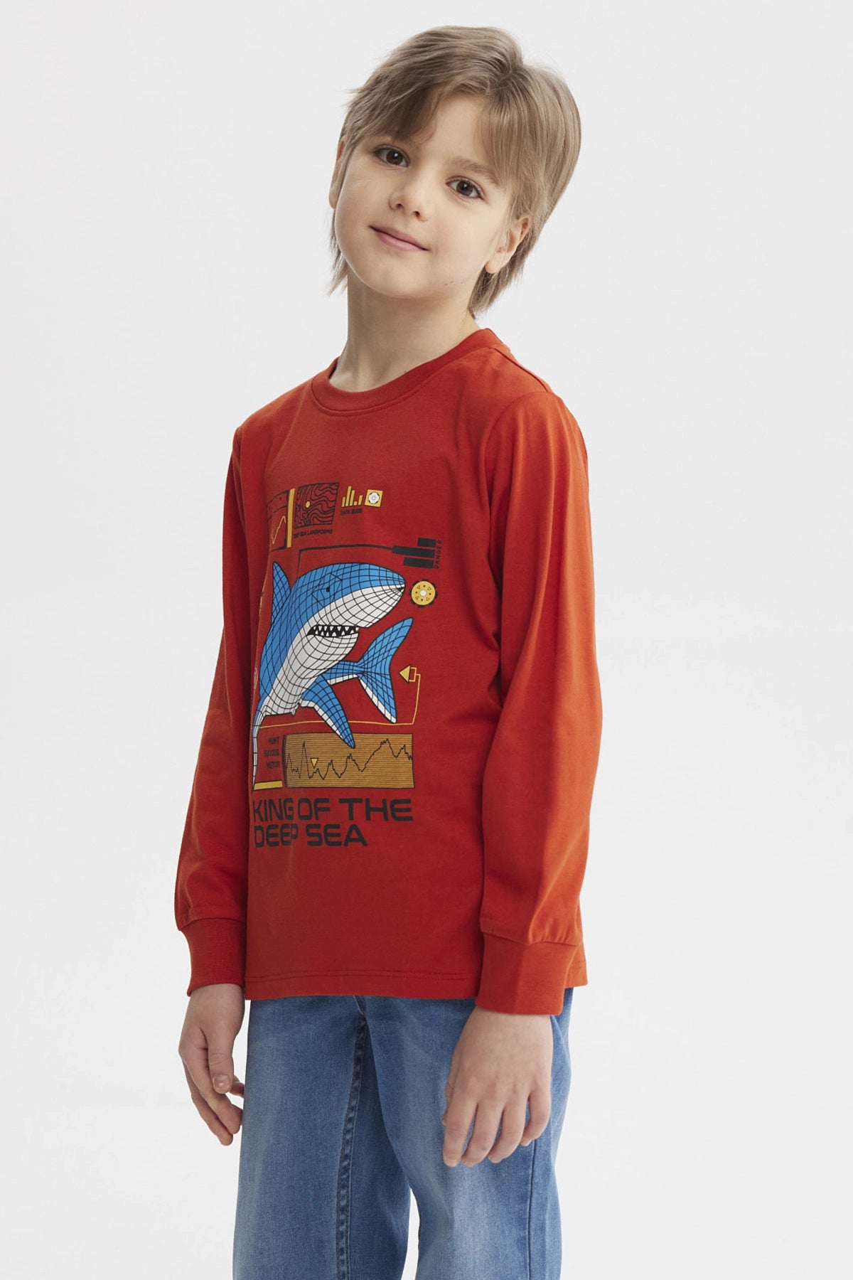 Polera de niño ocre con estampa grande de tiburón azul en estilo gráfico en el centro y texto King of the Deep Sea