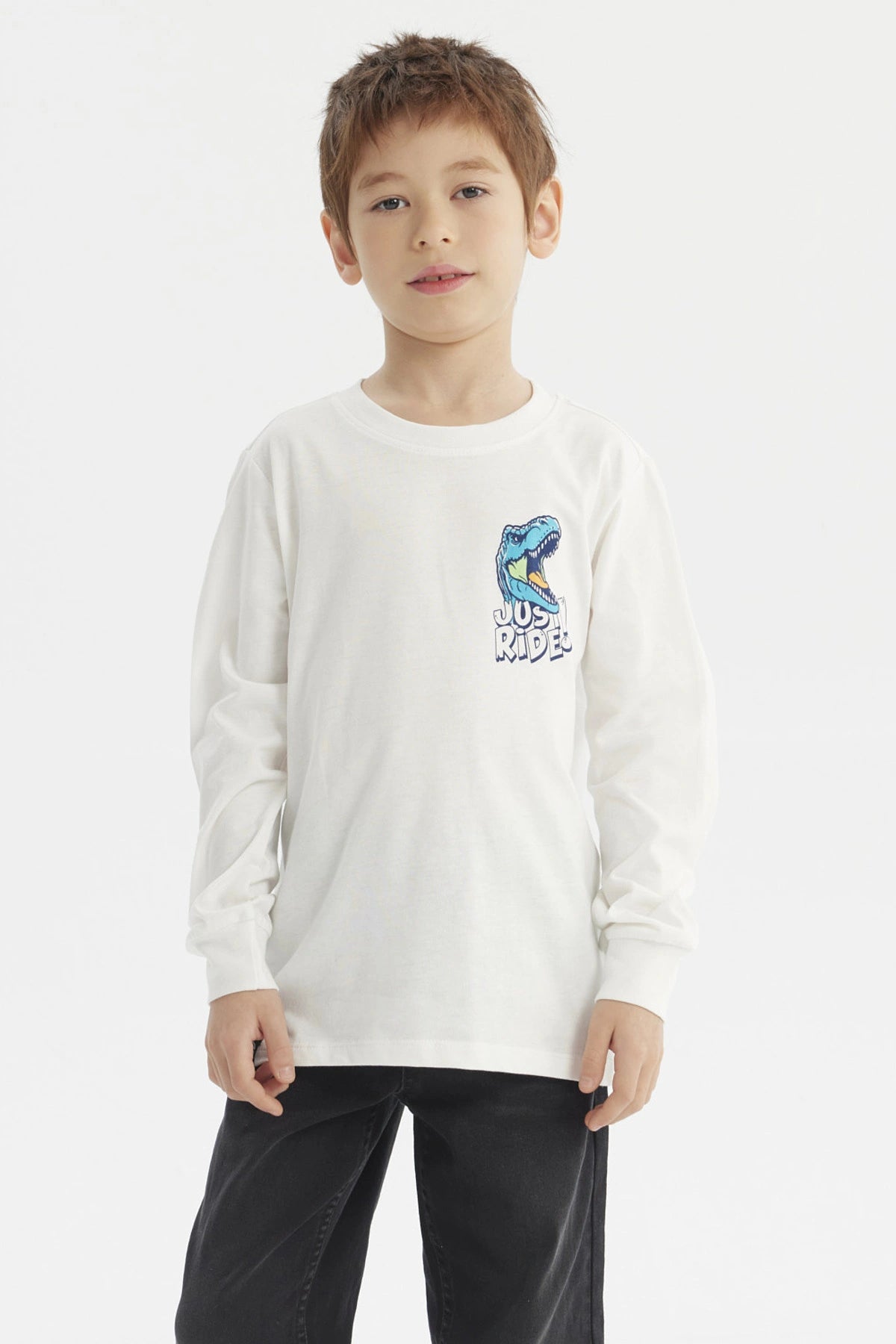 Polera crudo de niño con estampa de dinosaurio azul y texto Just Ride en el pecho estilo casual y gráfico