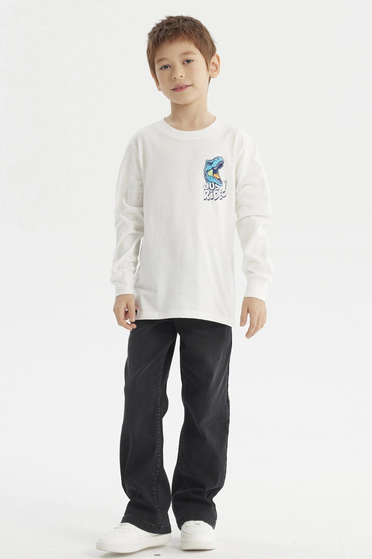 Polera crudo de niño con estampa de dinosaurio azul y texto Just Ride en el pecho estilo casual y gráfico