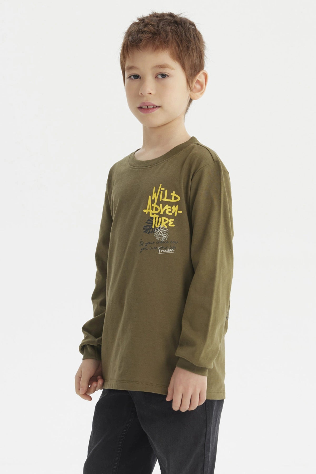 Polera verde militar para niño con texto Wild Adventure en amarillo en el pecho estilo casual y estampado pequeño