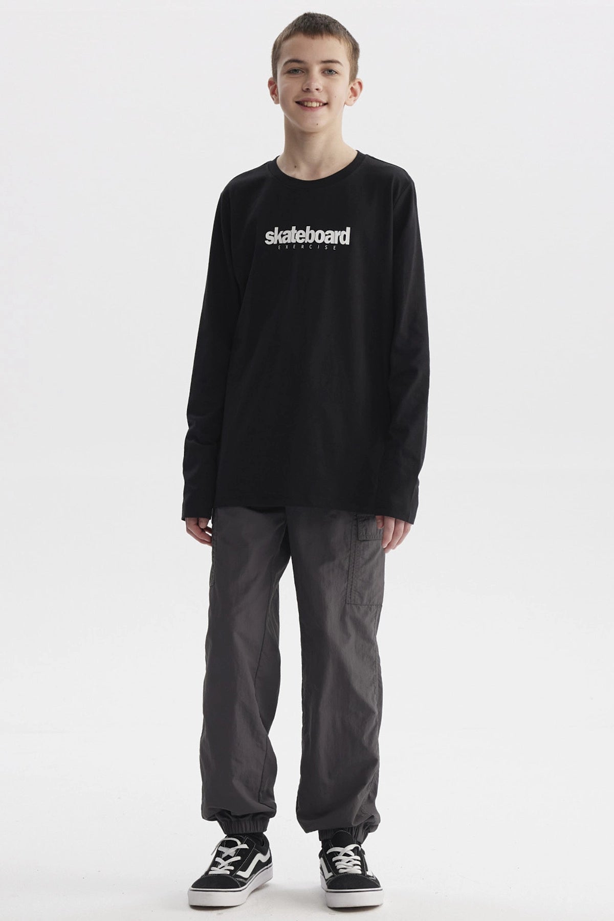 Polera negra de niño con texto blanco skateboard exercise en el pecho estilo casual urbano y manga larga lisa