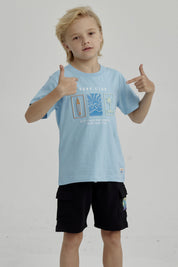 Polera celeste de niño con estampado frontal de surf club con tabla de surf ola y palmera diseño gráfico pequeño