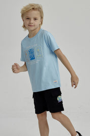 Polera celeste de niño con estampado frontal de surf club con tabla de surf ola y palmera diseño gráfico pequeño