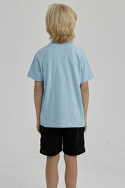 Polera celeste de niño con estampado frontal de surf club con tabla de surf ola y palmera diseño gráfico pequeño