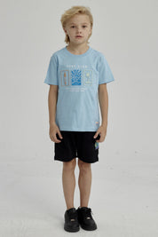 Polera celeste de niño con estampado frontal de surf club con tabla de surf ola y palmera diseño gráfico pequeño