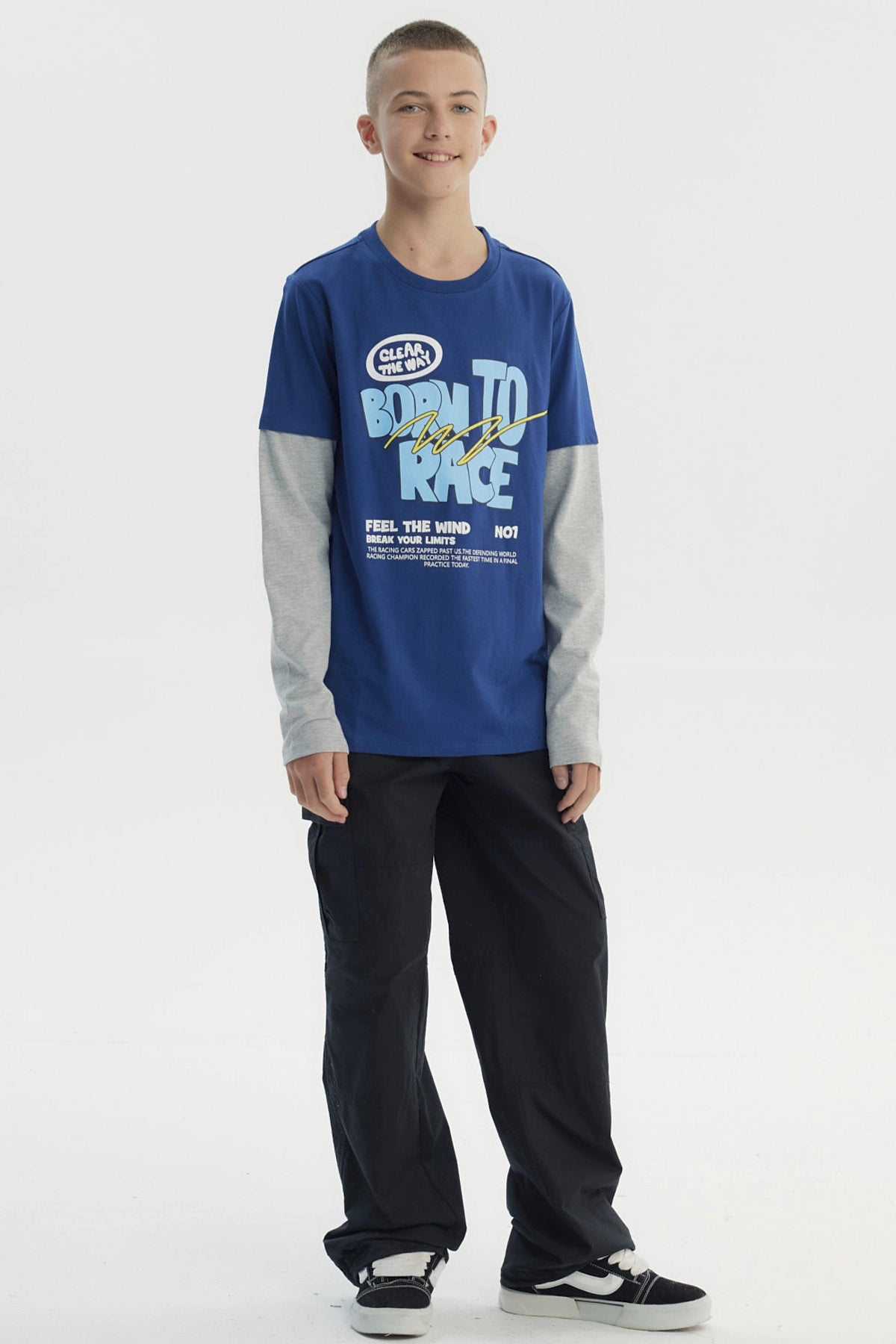 Polera niño azul con estampado frontal de letras en estilo gráfico grande y texto BORN TO RACE sobre fondo liso