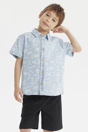 Camisa de niño celeste con estampado de dinosaurios blancos en estilo gráfico pequeño y disperso por toda la prenda