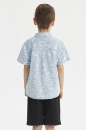 Camisa de niño celeste con estampado de dinosaurios blancos en estilo gráfico pequeño y disperso por toda la prenda