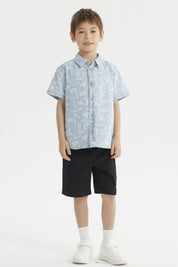 Camisa de niño celeste con estampado de dinosaurios blancos en estilo gráfico pequeño y disperso por toda la prenda