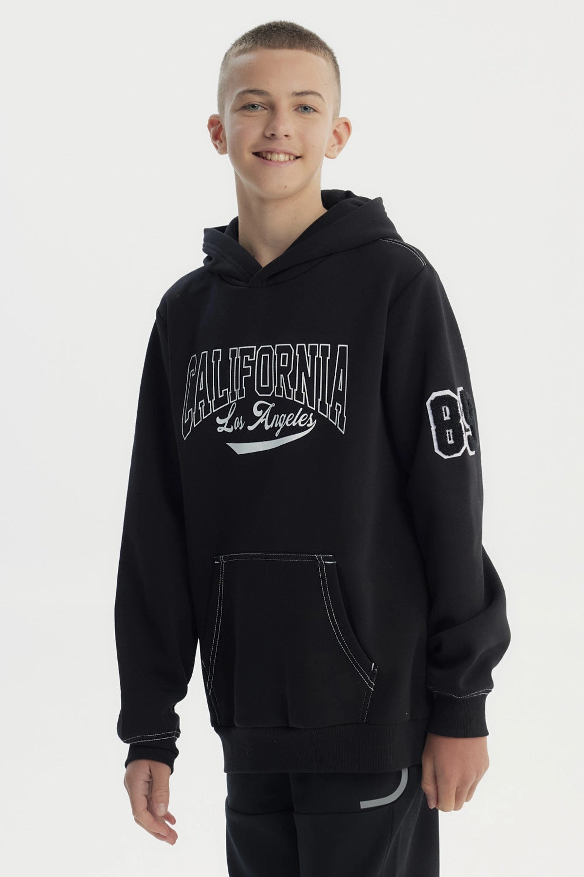Polerón niño negro con capucha y texto California Los Angeles en el pecho estilo universitario casual sin estampa adicional