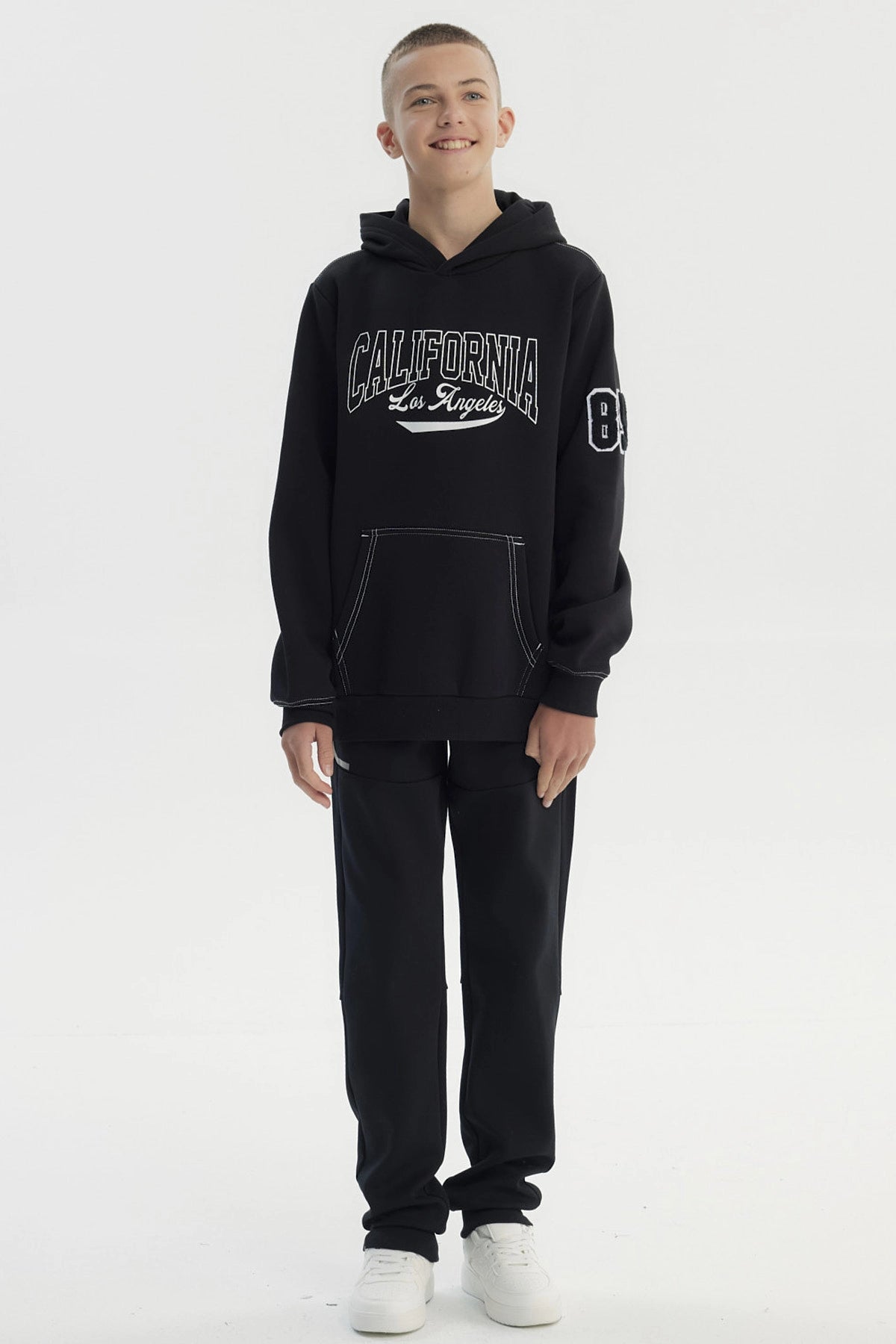 Polerón niño negro con capucha y texto California Los Angeles en el pecho estilo universitario casual sin estampa adicional
