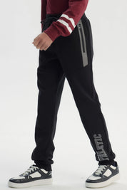 Pantalón buzo negro para niño con ajuste pitillo letras blancas en pierna izquierda estilo deportivo urbano