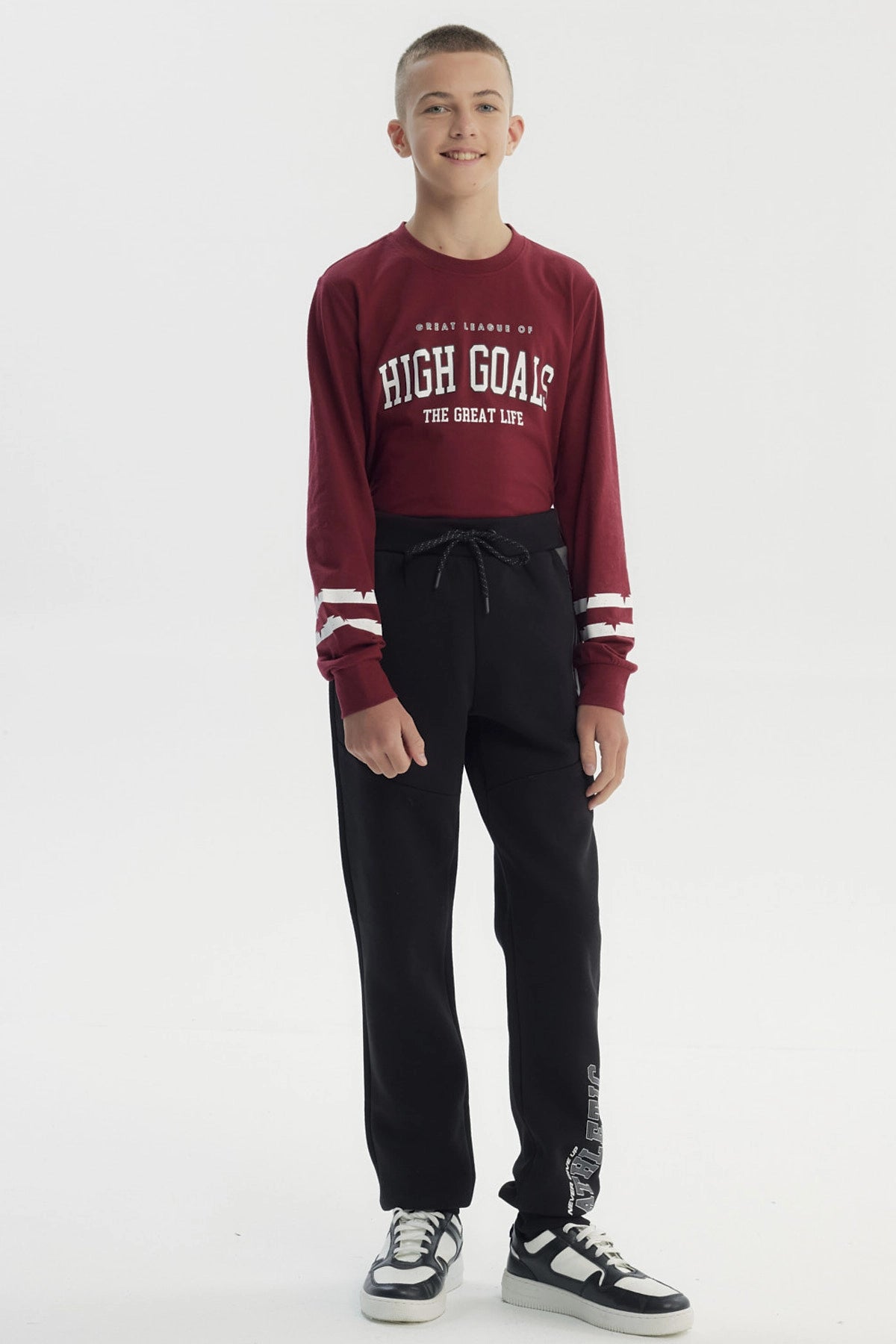 Pantalón buzo negro para niño con ajuste pitillo letras blancas en pierna izquierda estilo deportivo urbano