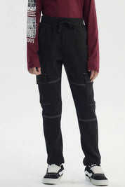 Pantalón buzo pitillo negro para niño con bolsillos laterales grandes y costuras blancas visibles estilo casual