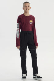 Pantalón buzo pitillo negro para niño con bolsillos laterales grandes y costuras blancas visibles estilo casual