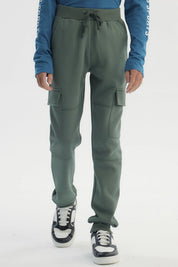 Pantalón buzo niño verde pitillo con bolsillos cargo en piernas diseño liso sin estampado ajuste con cordón