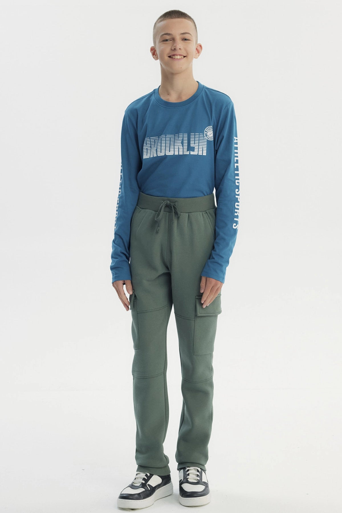 Pantalón buzo niño verde pitillo con bolsillos cargo en piernas diseño liso sin estampado ajuste con cordón