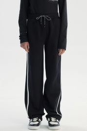 Pantalón buzo negro para niño con ajuste pitillo y rayas laterales blancas sin estampa visible