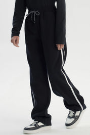 Pantalón buzo negro para niño con ajuste pitillo y rayas laterales blancas sin estampa visible