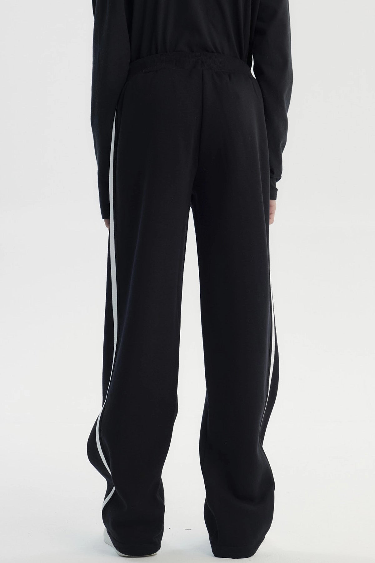 Pantalón buzo negro para niño con ajuste pitillo y rayas laterales blancas sin estampa visible