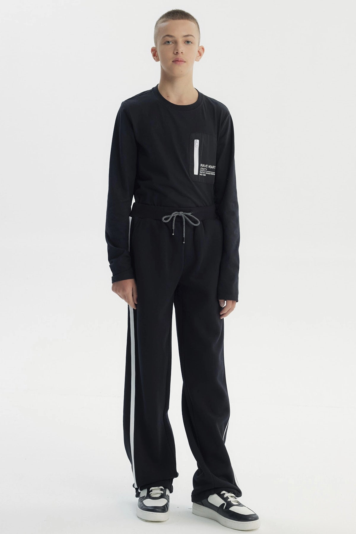 Pantalón buzo negro para niño con ajuste pitillo y rayas laterales blancas sin estampa visible