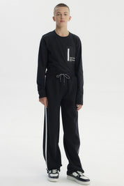 Pantalón buzo negro para niño con ajuste pitillo y rayas laterales blancas sin estampa visible